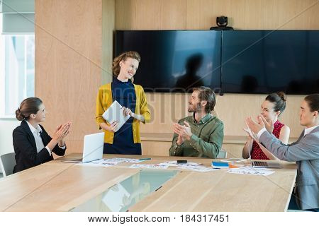 Business team applauding their colleague in conference room at office