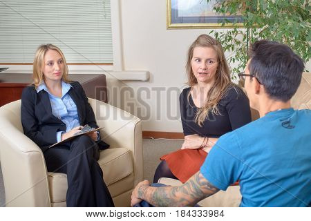 Young couple talking to therapist. Attractive ellegant woman listening attentively, taking notes.