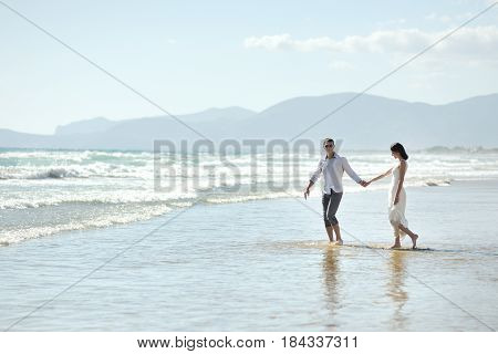 Couple walking holding hands on the beach of Sperlonga Italy Europe