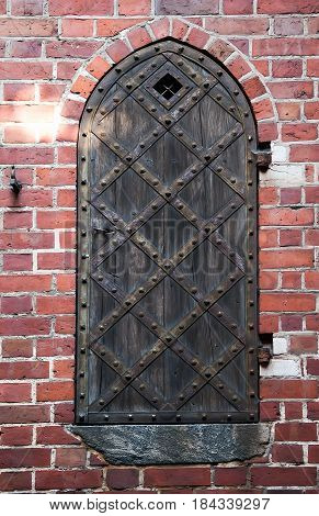 Old wooden door with brick arch facade