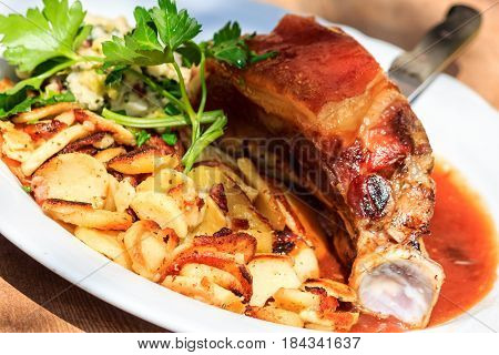 Traditional roasted pork Schaeufele Munich style with fried potatoes