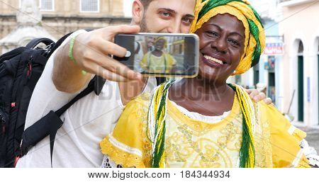 Tourist taking a selfie with a Baiana in the old colonial district of Salvador, Brazil