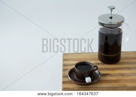 Cafetiere and a cup of black coffee on table against white background