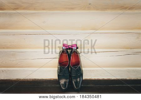 Men's lacquered black shoes on a wooden background. Groom's accessories.