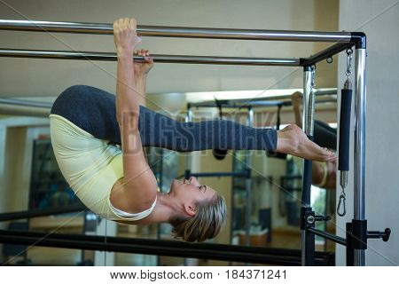 Determined woman performing stretching exercise on pilates cadillac in gym