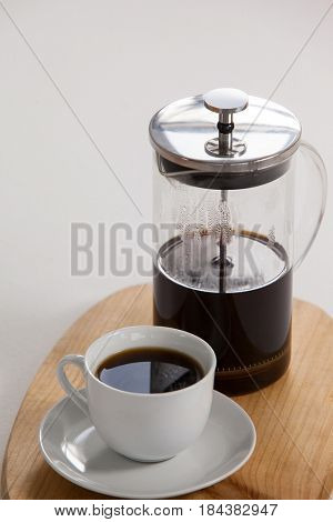 Cafetiere and a cup of black coffee on wooden tray