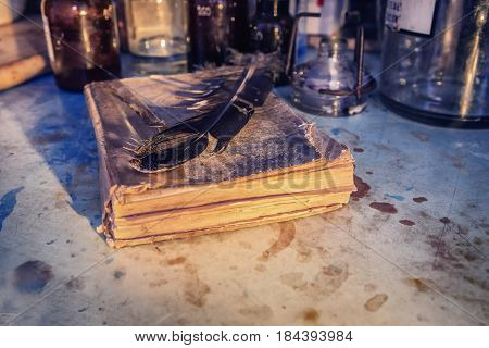 An old lab. The table of the alchemist. Laboratory table stained with chemicals and poisons. On the table of an old manuscript from a bird's feather. Objects and animals for the manufacture of substances.