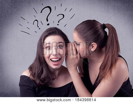 A teenager girl looking confused with drawn question marks above the head, while a girlfriend whispers something in her ear concept.