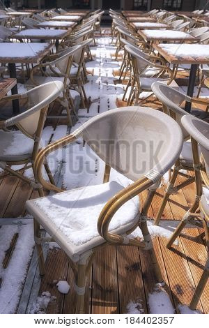 Snow fell on rattan chairs and tables in the street cafes of the city of Riga in early spring