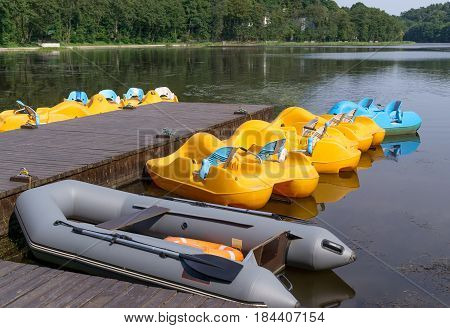 Pedalos and inflatable boat parked at wooden pier on lake