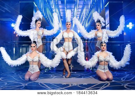 Group of carnival dancers performing in smoke and artistic lighting wearing beautiful white matching outfits sexy hot seductive confident professional beauty lifestyle celebration entertain concept.