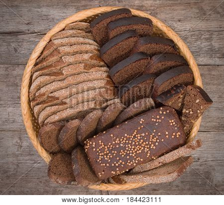 Wicker Basket, Breadbasket, Bread-plate With Slices Of Dark Bread On Rustic Wooden Boards Background