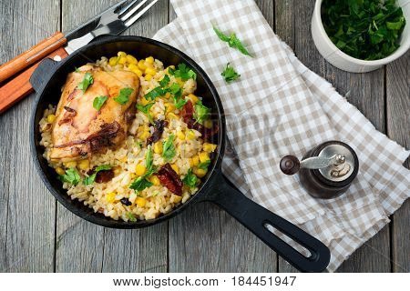 Rice with corn soy sauce and fried chicken thigh on a cast-iron frying pan. Top view. Selective focus.