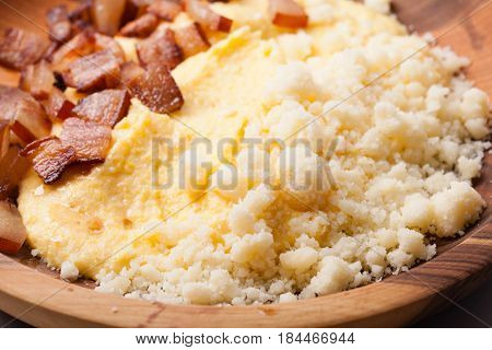 Polenta with bacon and salted cheese on the wooden table - traditional Carpathian dish