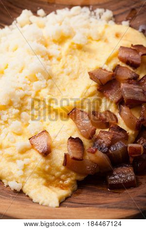 Polenta with bacon and salted cheese on the wooden table - traditional Carpathian dish