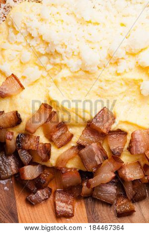 Polenta with bacon and salted cheese on the wooden table - traditional Carpathian dish