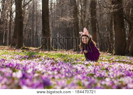 Little girl with banny ears peeping from behind a tree in the park