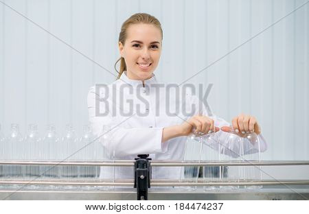 Female worker placing empty bottles on the line at a water factory