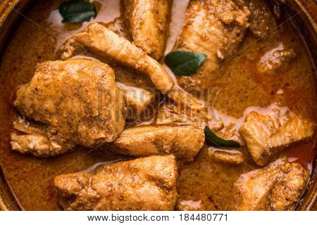 tasty fish curry served with white cooked basmati rice with curry leaves in the background, favourite coastal indian food