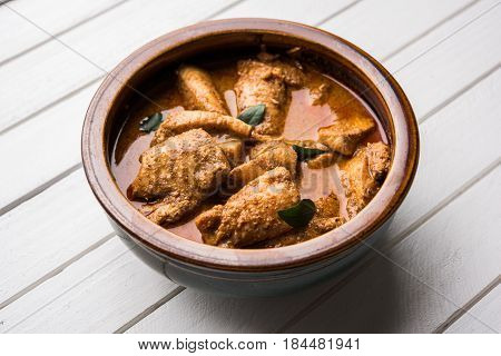 tasty fish curry served with white cooked basmati rice with curry leaves in the background, favourite coastal indian food