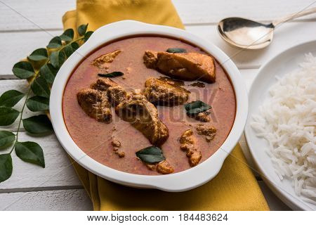 tasty fish curry served with white cooked basmati rice with curry leaves in the background, favourite coastal indian food