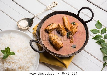tasty fish curry served with white cooked basmati rice with curry leaves in the background, favourite coastal indian food