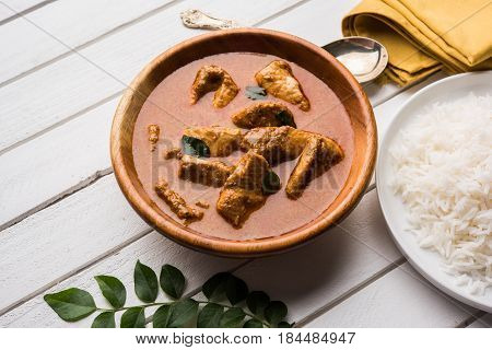 tasty fish curry served with white cooked basmati rice with curry leaves in the background, favourite coastal indian food