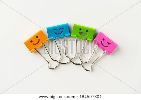 Business concept - Top view of four cute and colourful smile metal clip on white background desk for mockup