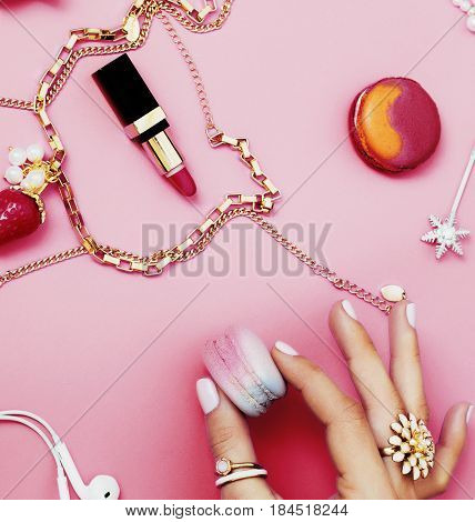 woman hands holding macaroons with lot of girl stuff on pink background, girls accessories concept close up