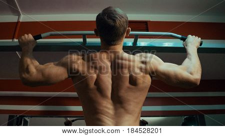 Strong man doing pull-ups in the gym