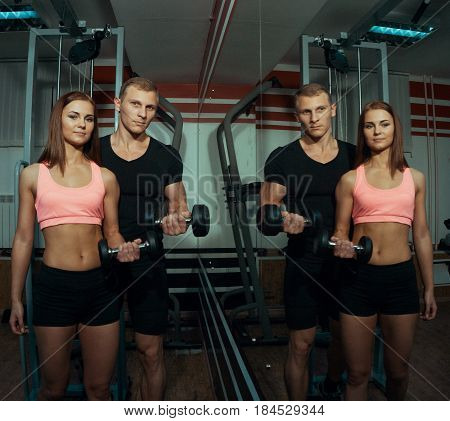 Man and woman doing exercise with dumbbells in the gym.