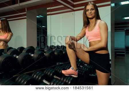 Sport girl near a dumbbell in the gym.