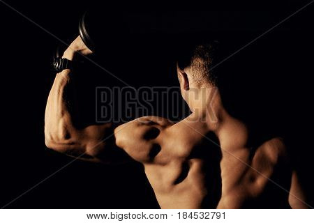 Bodybuilder with dumbbells on a dark background.