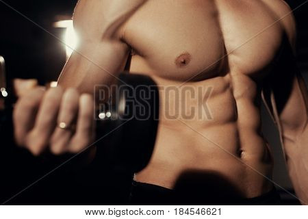 Muscular male bodybuilder working out in gym, exercising biceps