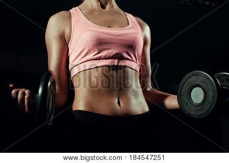 Beautiful body of a young woman with dumbbells in his hands.