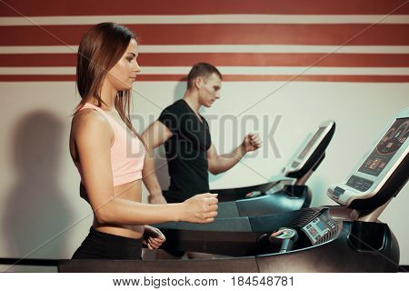 Man and woman running on a treadmill in the gym