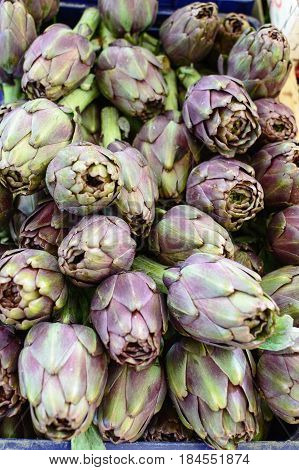 Some artichokes stacked in a vegetable market