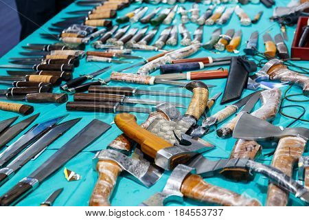 Hunting knives and knifes of large and small sizes lie on a table in a hunting and fishing store