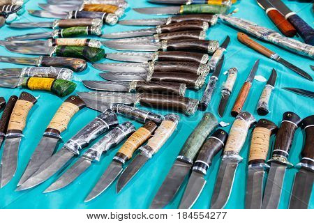 Hunting knives and knifes of large and small sizes lie on a table in a hunting and fishing store