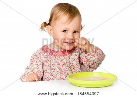 Funny child eating porrige with spoon, isolated over white