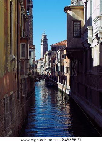 canal in venice with shadows on a sunny day with campanile