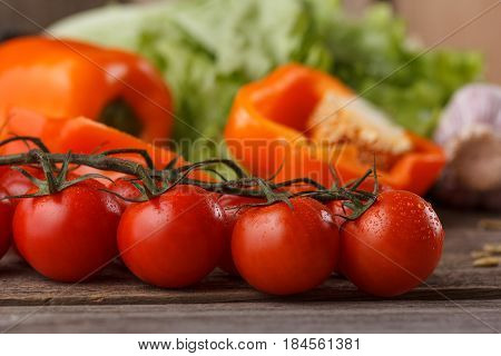Fresh, Ripe Cherry Tomatoes On An Old Wooden Background. Vegetables Leave In The Background.
