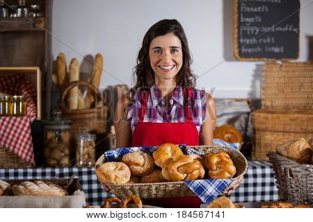 Female staff holding basket of sweet foods in bakery section of supermarket