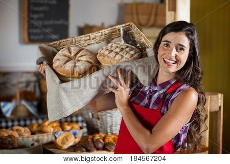 Female staff holding basket of sweet foods in bakery section of supermarket