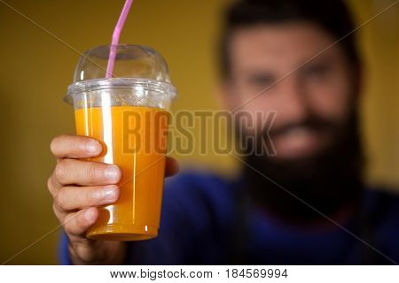 Male staff holding orange juice glass at organic section of supermarket