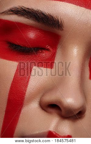 Beauty fashion female Model with red painted Geometry on Face and closed Eyes