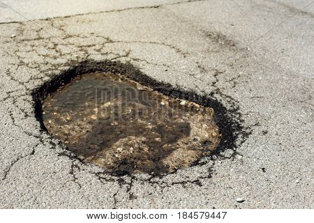 Asphalt road hole damage close up of damaged driveway