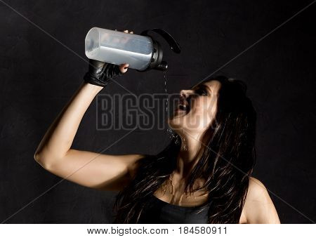 sporty female boxer or mma fighter drinking and splashing water in her face. beautiful female fitness woman on black background