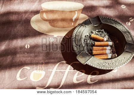Various cigarette butts in full ashtray on table
