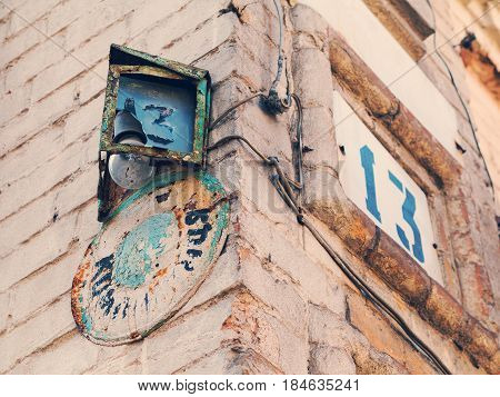 Retro metal plate with drawings 13 on white brick wall at the corner of an old house the index of the house number and the street name badly damaged. Suitable as background for any your project.